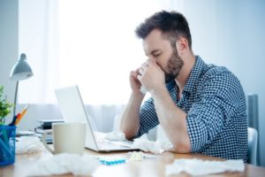 man suffering from a sinus infection at work