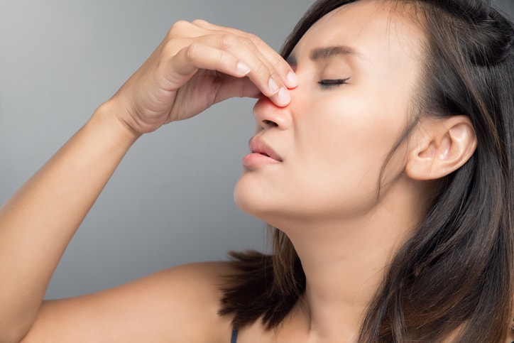 Asian woman pinches hurt her nose