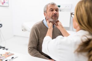 Female Doctor Doing Throat Examination On Older Man