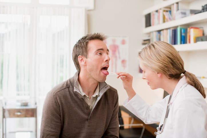 Female Doctor checking male patients throat