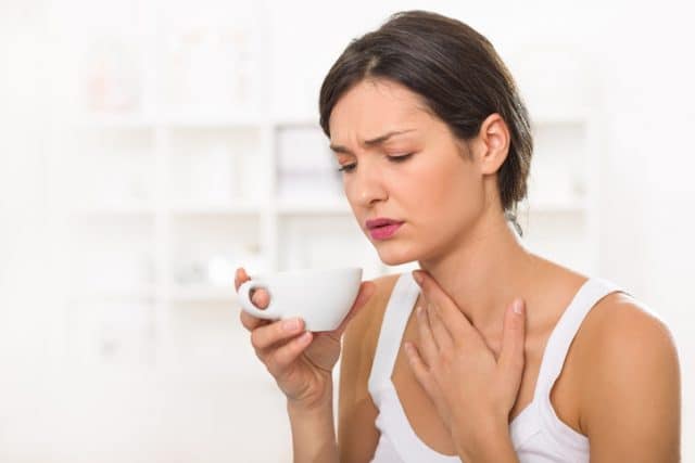 Young woman with a sore throat drinking tea