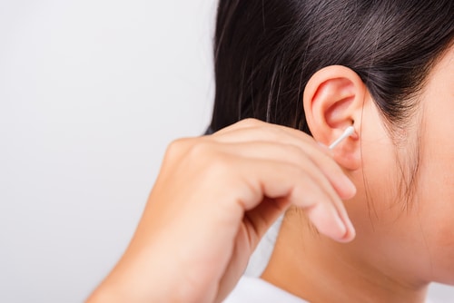 woman cleaning ear hrt using cotton swab